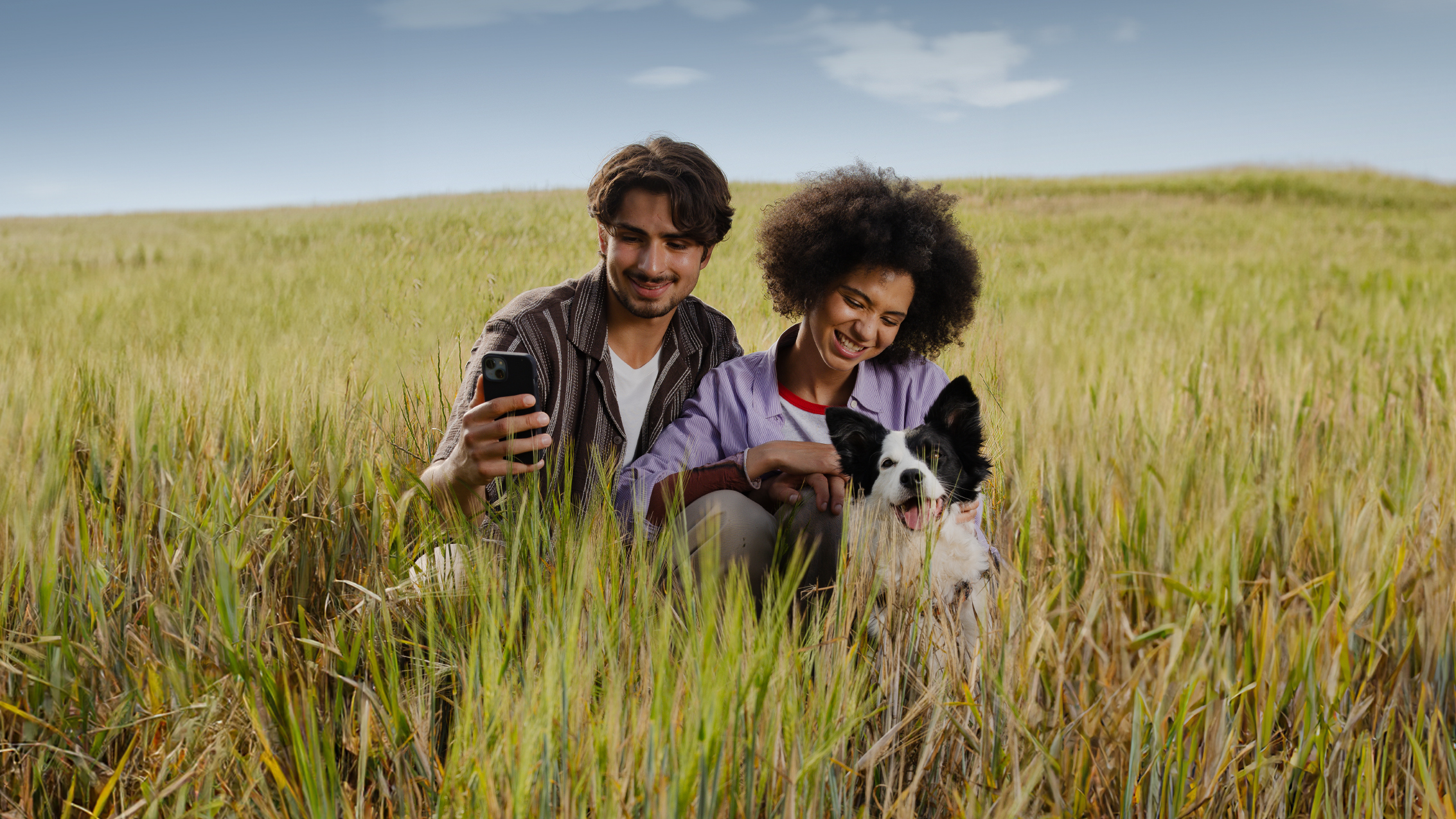 Paar mit Hund sitzen in hoher Wiese